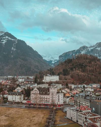 Aerial view of Interlaken, Switzerland surrounded by snow-capped Alps, showcasing urban buildings and natural beauty.