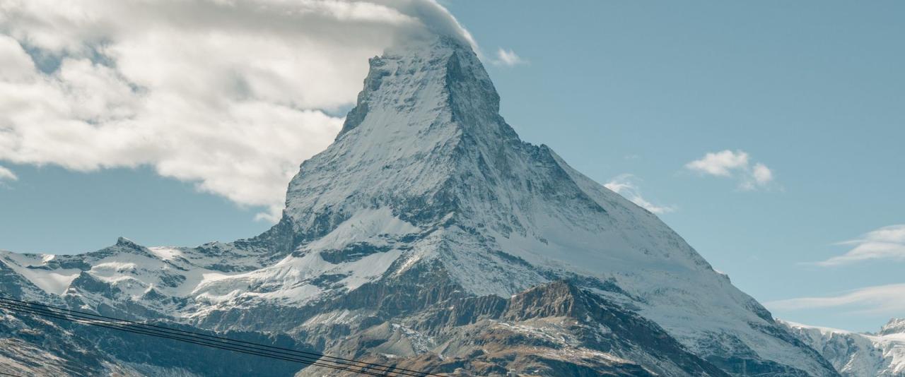 Stunning view of the Matterhorn in Zermatt, Switzerland with a cloud-capped peak on a clear day.