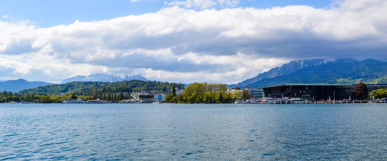 Idyllic view of a Swiss lakeside town with mountains and clouds.