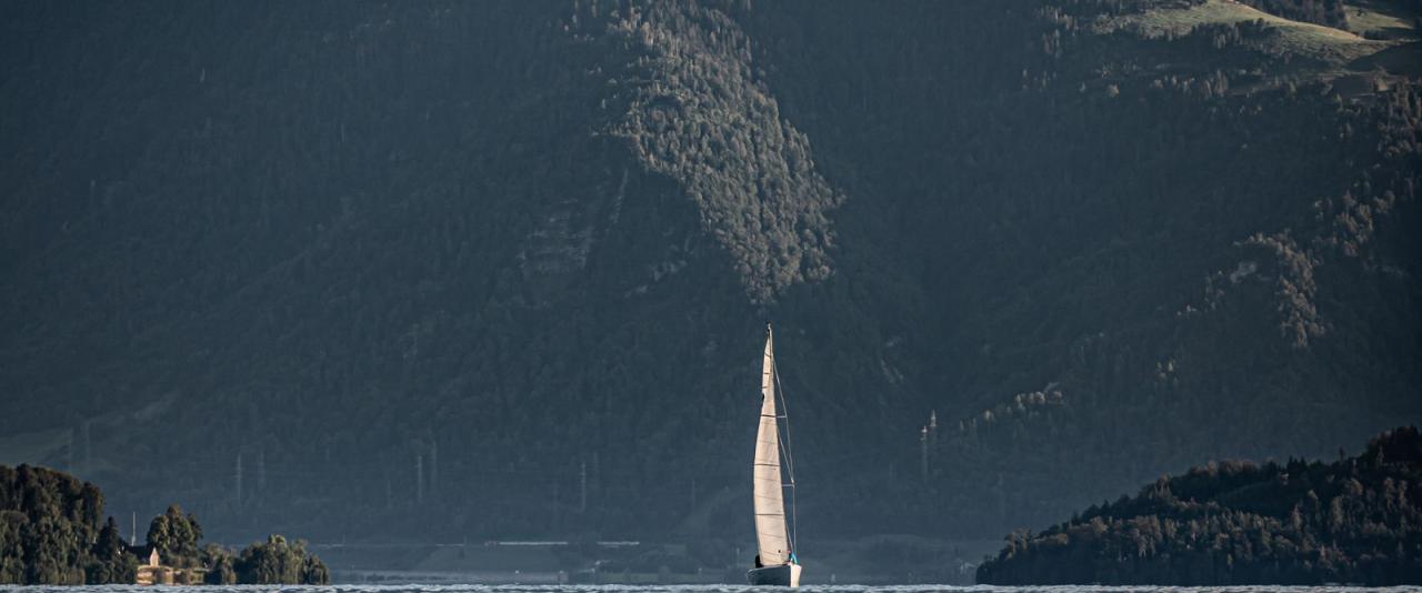 A tranquil sailboat on Lake Zug with breathtaking mountain views, capturing the essence of Swiss natural beauty.