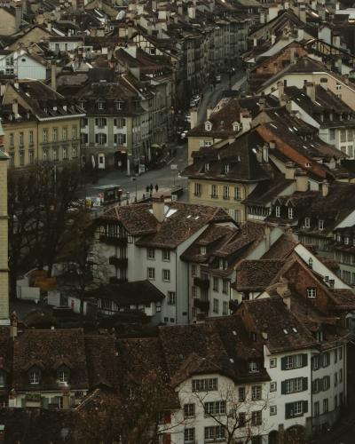 A view of the Aare River in Bern, Switzerland, featuring the historic Nydeggbrücke bridge and traditional buildings with terracotta roofs along the riverbank.