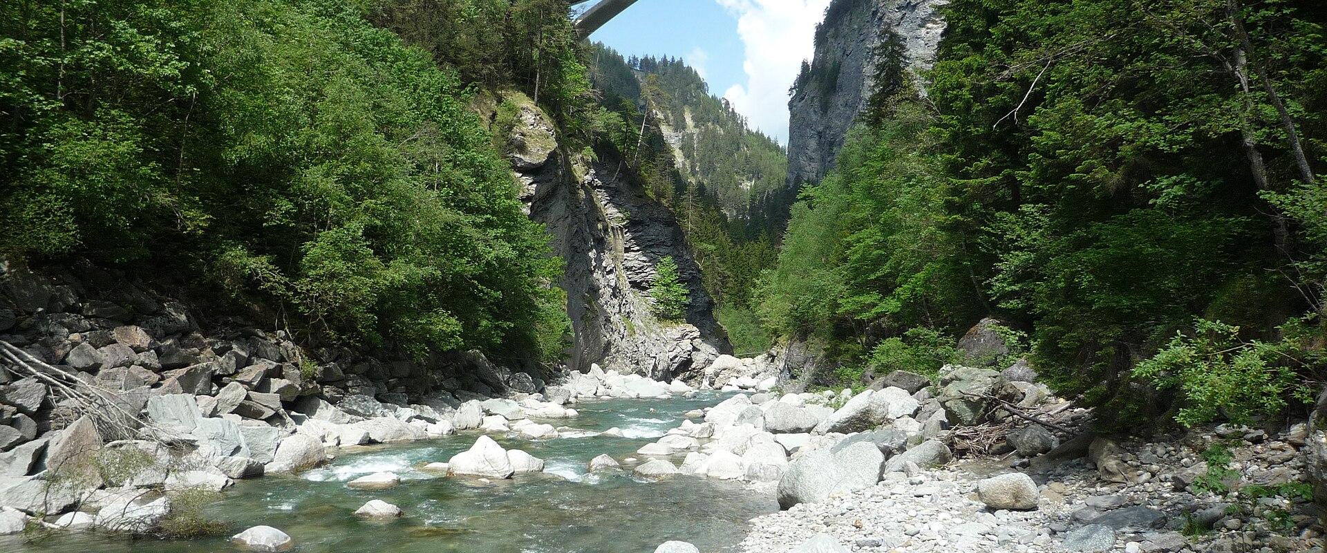 The Hinterrhein flowing over boulders at the bottom of the Viamala gorge, spanned by a high bridge