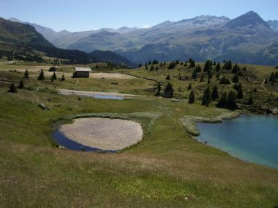 Small alpine lakes of Lais Blos on the Alp Flix plateau above Sur, Graubünden, with a hut and mountains beyond