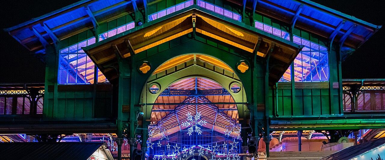 The covered market hall in Montreux lit up in colour at night during the Montreux Noël Christmas market
