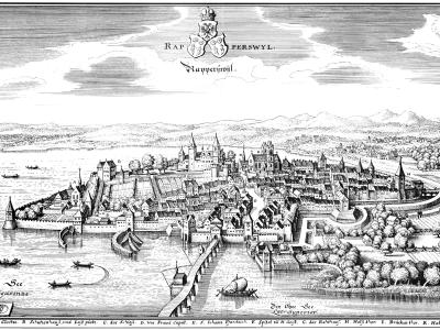 A black-and-white historical engraving depicting a fortified medieval town on a peninsula extending into a large lake, with ships on the water and mountains in the background.
