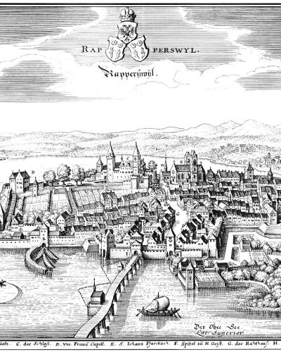 A black-and-white historical engraving depicting a fortified medieval town on a peninsula extending into a large lake, with ships on the water and mountains in the background.