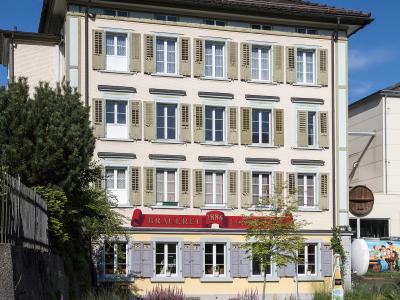 A multi-story cream-colored building with green shutters and a prominent red sign reading "BRAUEREI 1886 LOCHER" on the facade.