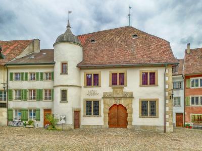 A historic white building with a round tower and a large wooden gate, featuring the text "STADT MUSEUM" on the facade.