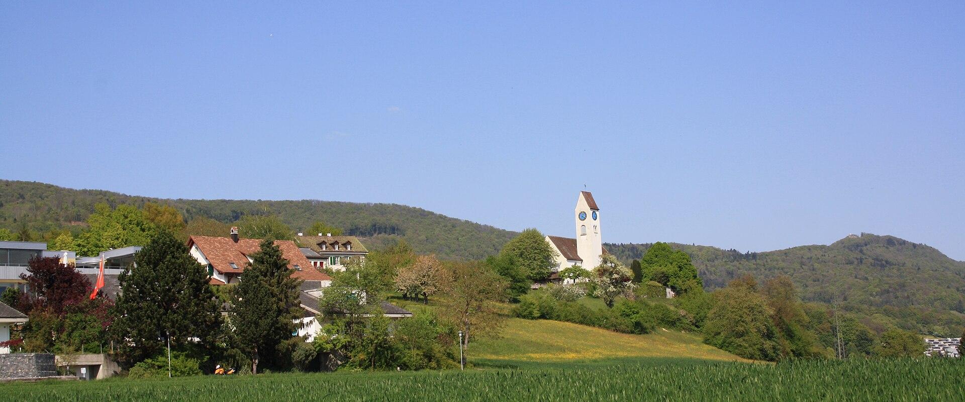 The village of Küttigen and its hilltop church above green meadows