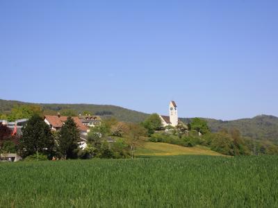 The village of Küttigen and its hilltop church above green meadows