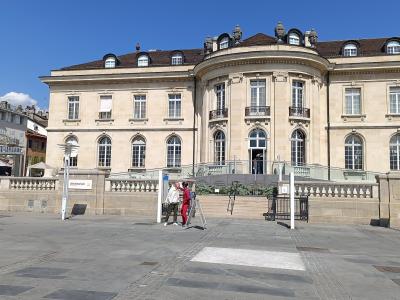 A large, light-colored stone building with classical architecture featuring a prominent curved central section and mansard roof, with a sign reading "alimentarium" visible on a low wall in the foreground.
