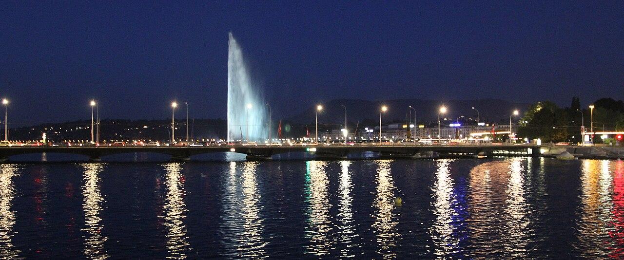 The Jet d'Eau and the lights of Geneva reflected in the lake at blue hour