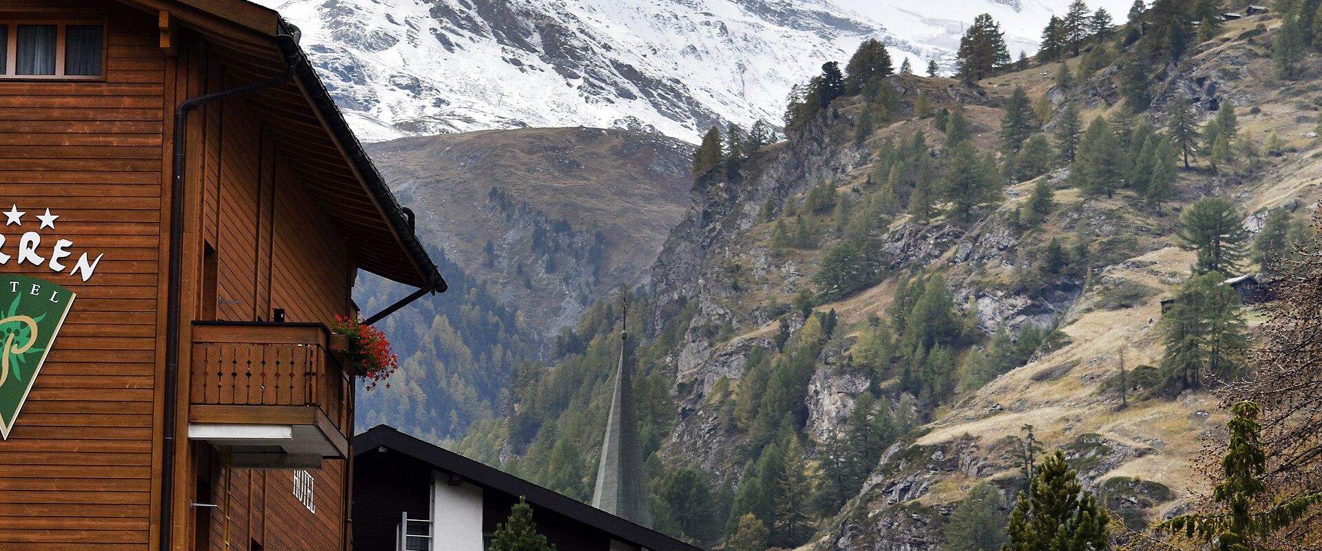 A view of a traditional wooden hotel building in the foreground with the iconic, snow-capped Matterhorn mountain rising prominently in the background.