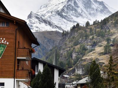 A view of a traditional wooden hotel building in the foreground with the iconic, snow-capped Matterhorn mountain rising prominently in the background.